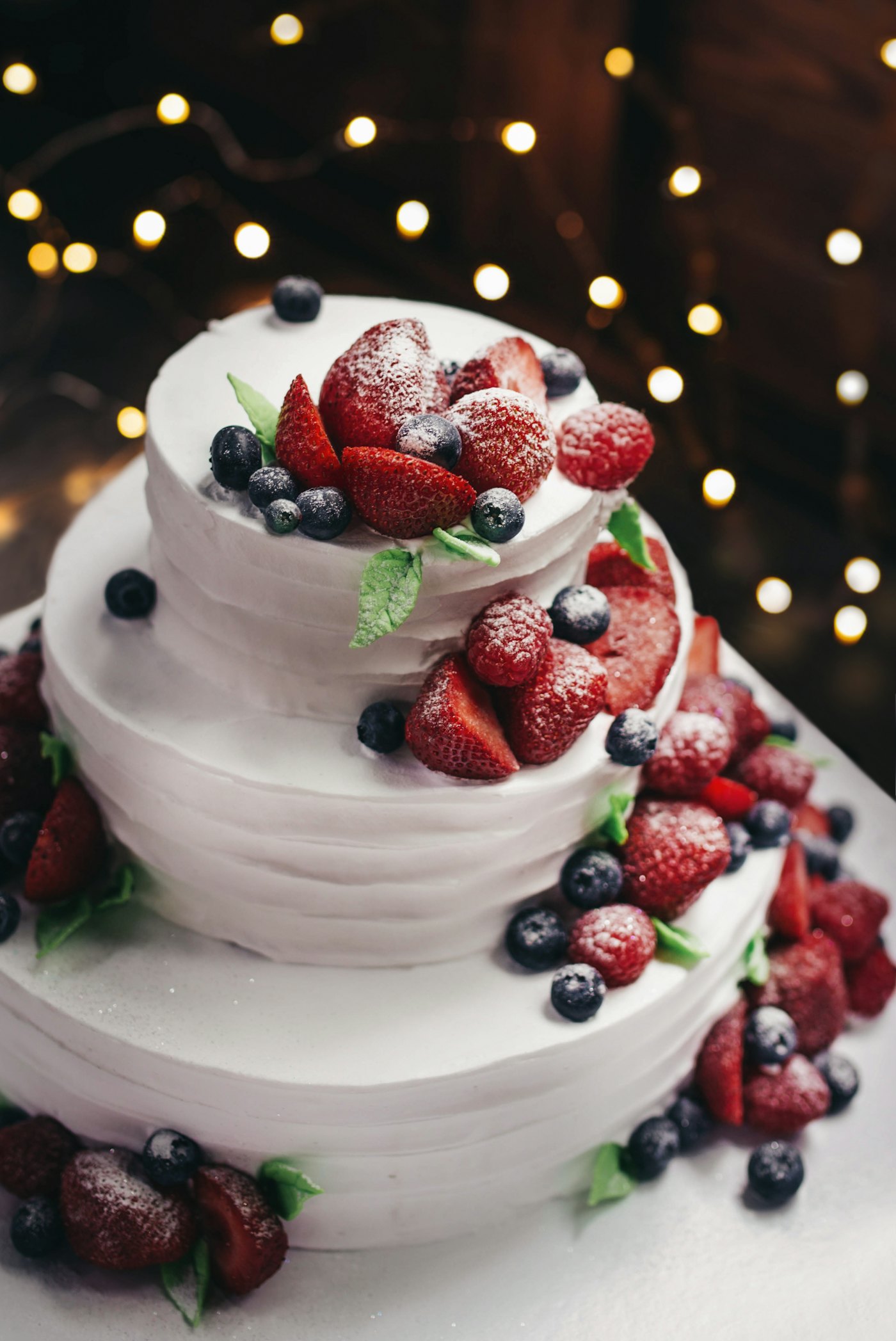 A naked celebration cake topped with fresh berries