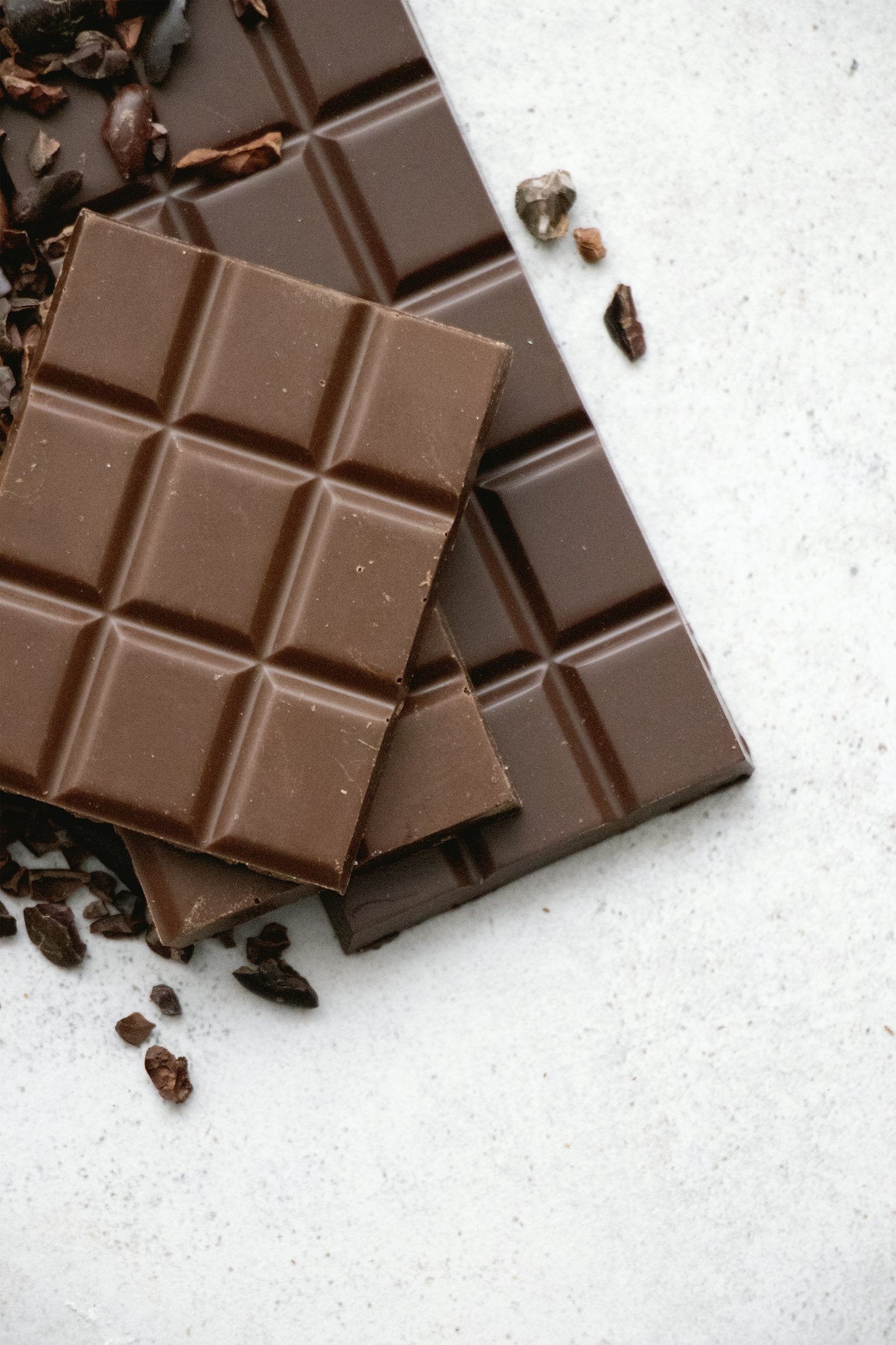Smooth glossy milk chocolate slab with cocoa nibs pressed into the surface